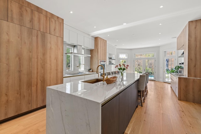 355 Greens Farms Rd, Westport, CT 06880 - kitchen featuring light stone counters, oven, modern cabinets, a large island with sink, and light wood-style flooring