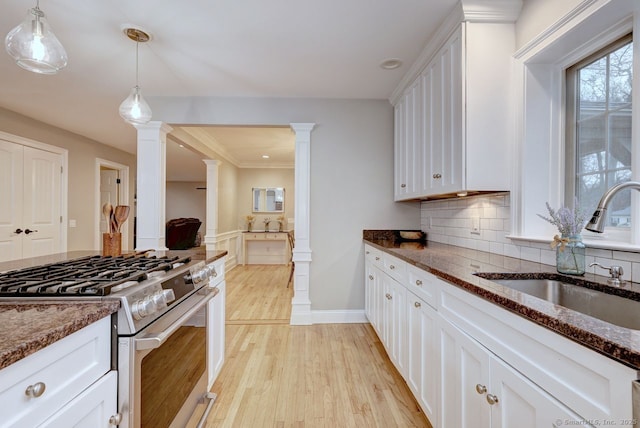 110 Far Mill Dr, Stratford, CT 06614 - kitchen with dark stone counters, gas stove, a sink, and white cabinets
