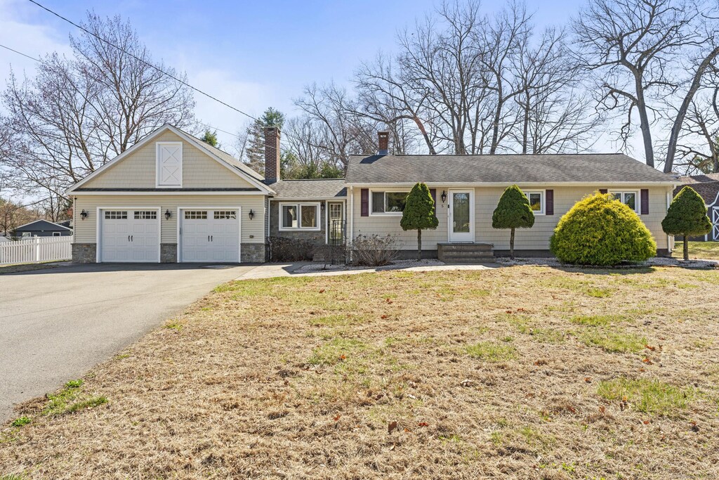 ranch-style house featuring stone siding, aphalt driveway, fence, an attached garage, and a chimney
