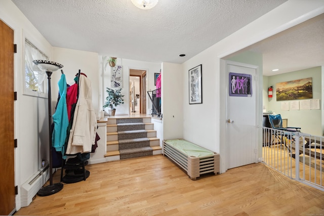 interior space featuring recessed lighting, a textured ceiling, a baseboard heating unit, and wood finished floors