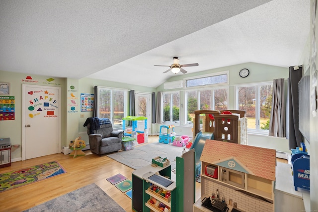 playroom featuring a textured ceiling, a ceiling fan, wood finished floors, and lofted ceiling
