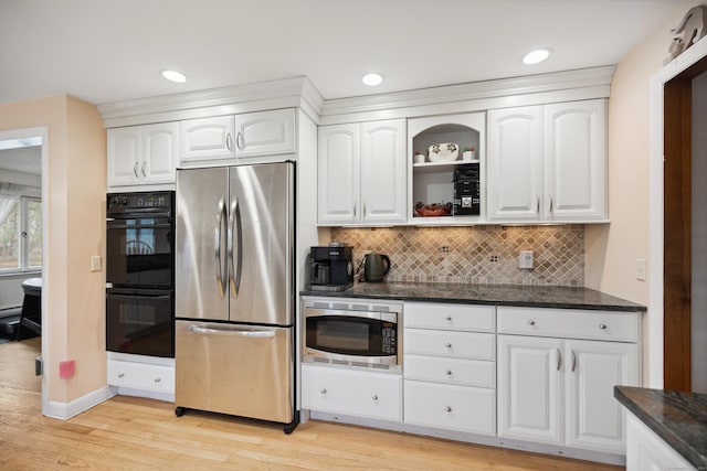 kitchen with backsplash, appliances with stainless steel finishes, light wood-type flooring, white cabinets, and dark stone countertops