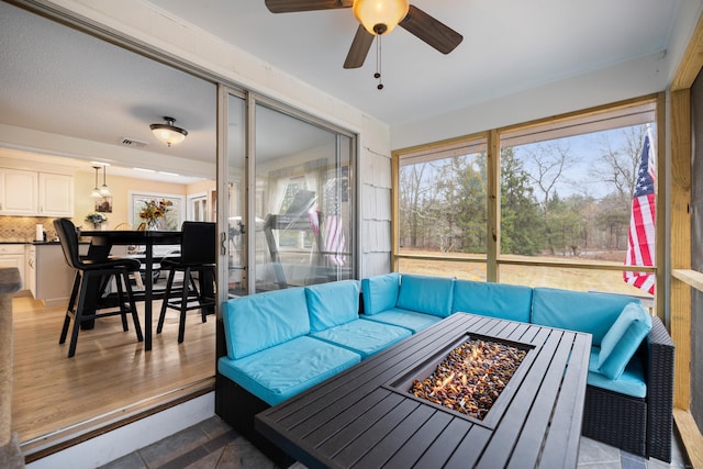 sunroom featuring a ceiling fan, an outdoor living space with a fire pit, visible vents, and outdoor dining space