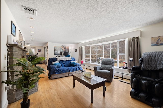 living area with visible vents, wood finished floors, baseboard heating, a textured ceiling, and a baseboard radiator