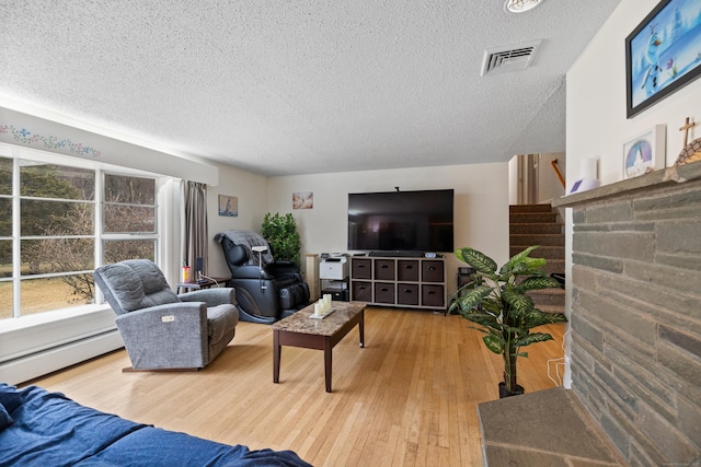 living room with stairway, a baseboard radiator, a textured ceiling, and visible vents