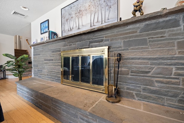 details featuring wood finished floors, a fireplace, a textured ceiling, and visible vents