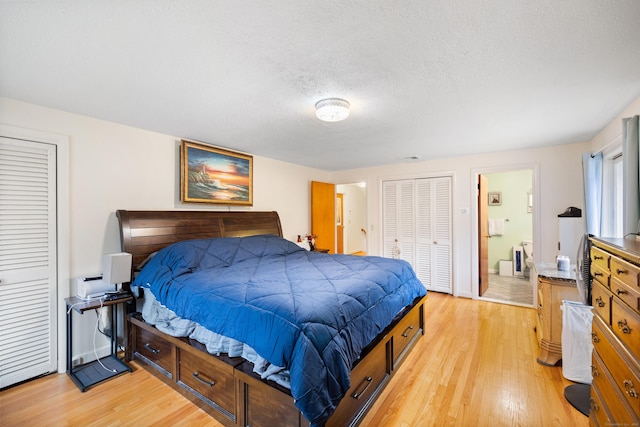 bedroom with a textured ceiling, light wood finished floors, and ensuite bath