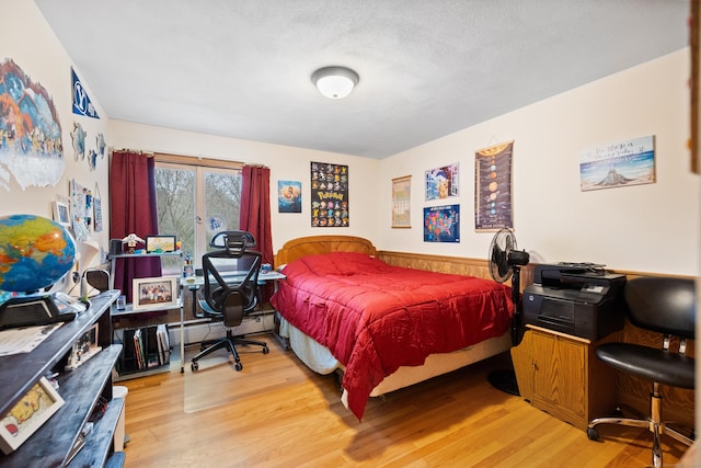bedroom with wainscoting and wood finished floors