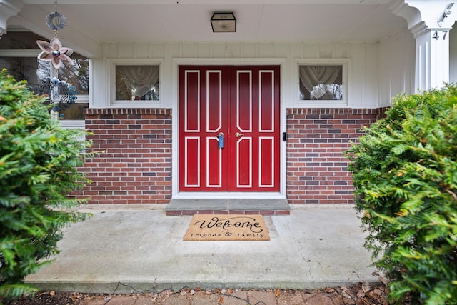 view of exterior entry with a porch and brick siding