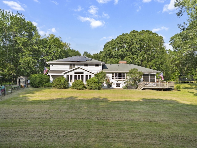 47 Notch Rd, Simsbury, CT 06092 - rear view of house with a deck, solar panels, a lawn, and a chimney