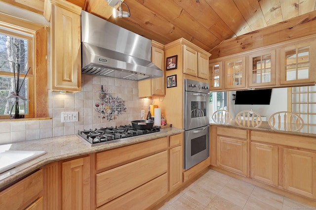 kitchen featuring light brown cabinetry, stainless steel appliances, ventilation hood, backsplash, and wood ceiling