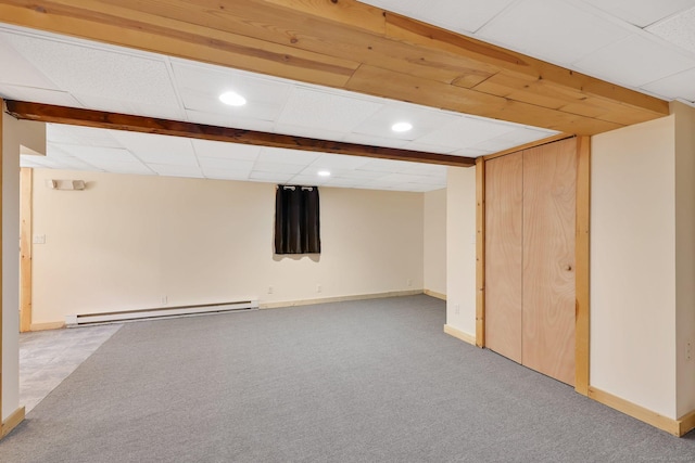 finished below grade area with a baseboard radiator, carpet floors, baseboards, and a paneled ceiling