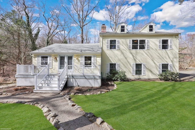 view of front of property with a wooden deck, a front yard, and a chimney