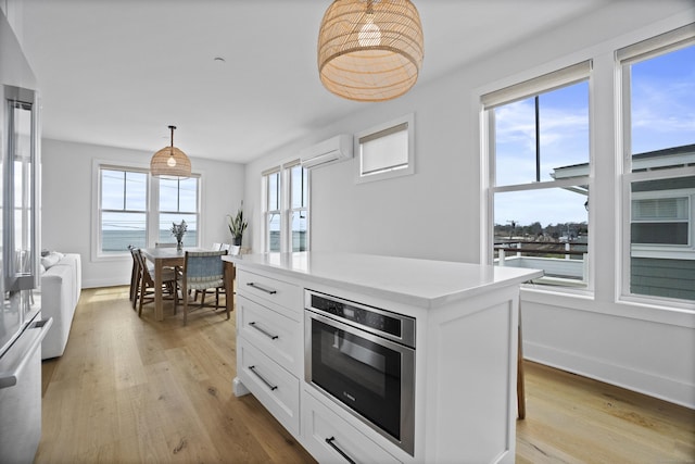 185 Main St Apt 301, East Lyme, CT 06357 - kitchen with light wood-style floors, light countertops, a wall unit AC, white cabinets, and stainless steel appliances