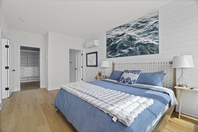 185 Main St Apt 301, East Lyme, CT 06357 - bedroom featuring an AC wall unit, wood walls, a walk in closet, and wood finished floors