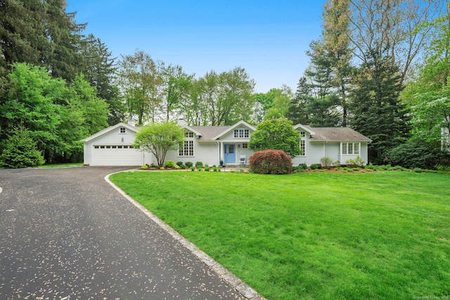 view of front facade with driveway, a front lawn, an attached garage, and view of scattered trees