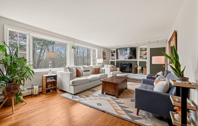 living area featuring built in shelves, light wood finished floors, and a fireplace