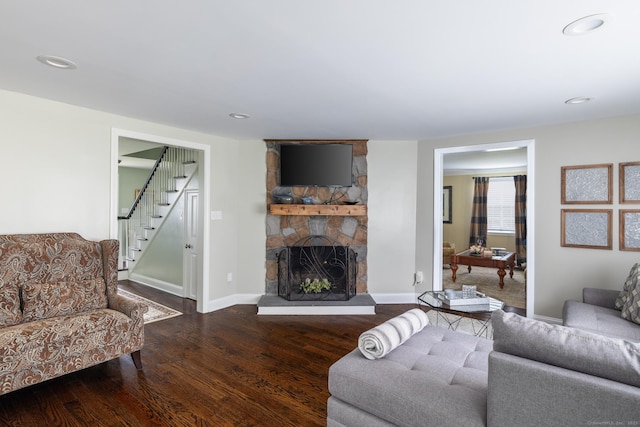 living area featuring a stone fireplace, stairway, wood finished floors, and baseboards