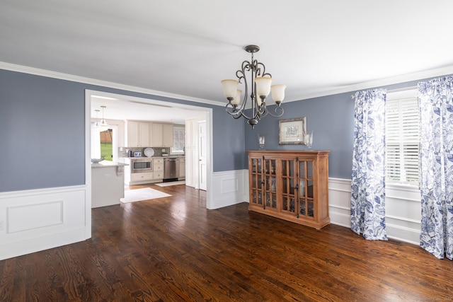 unfurnished dining area with crown molding, a notable chandelier, and wainscoting