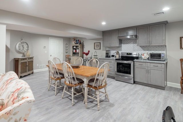 dining area featuring a toaster, visible vents, light wood-style flooring, and baseboards
