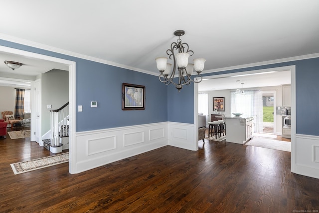 dining space with stairway, wood finished floors, a wainscoted wall, and a notable chandelier