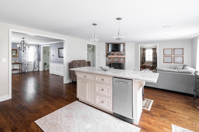 kitchen featuring pendant lighting, dark wood-style floors, open floor plan, a notable chandelier, and a stone fireplace