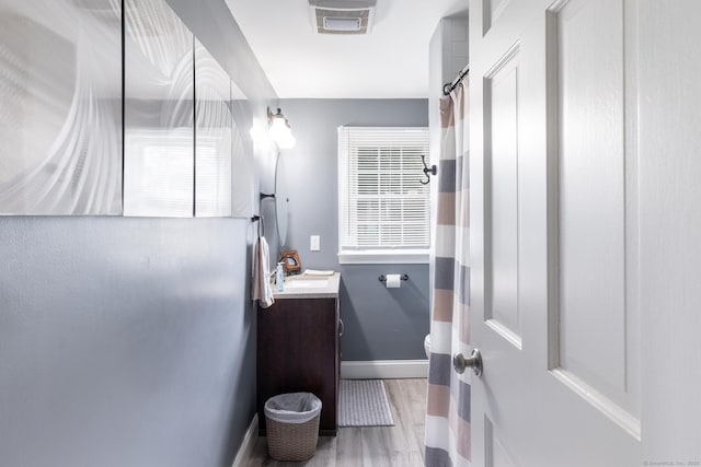 full bath with vanity, toilet, visible vents, baseboards, and wood finished floors
