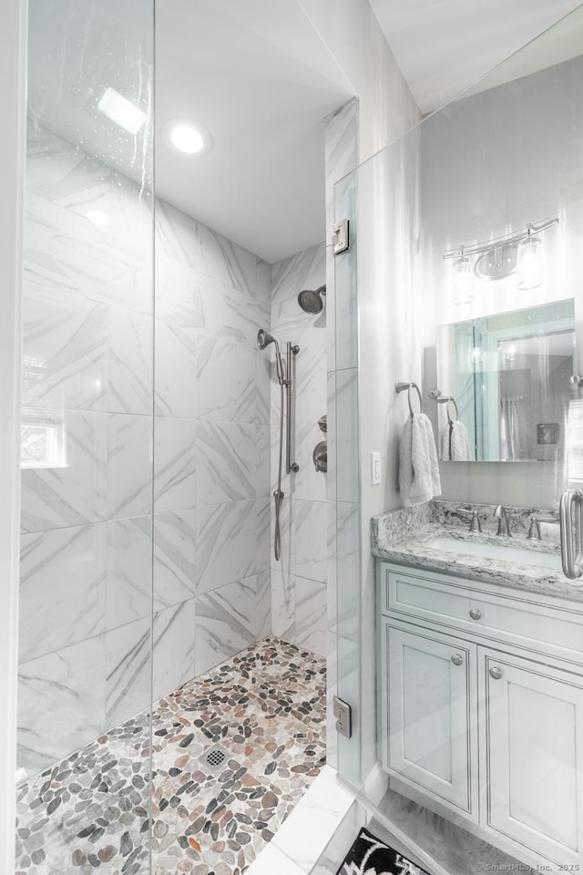 bathroom with vanity and a marble finish shower