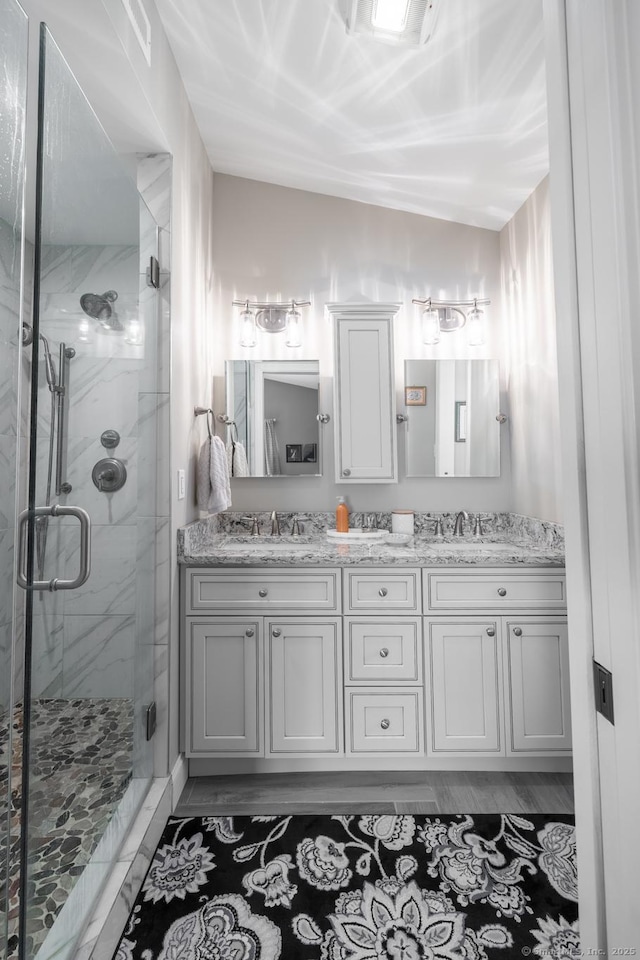 bathroom with a marble finish shower, double vanity, and a sink