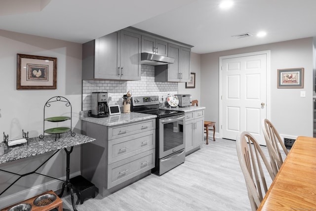 kitchen with electric stove, under cabinet range hood, light wood-type flooring, backsplash, and gray cabinetry