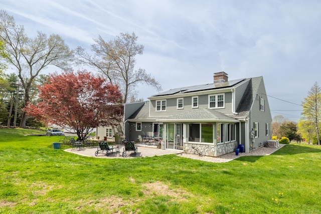 rear view of house featuring an outdoor fire pit, a yard, a shingled roof, a patio, and solar panels