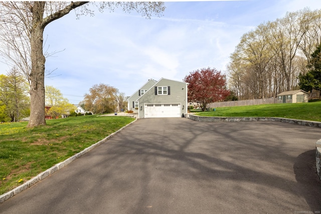 view of side of home featuring a garage, fence, aphalt driveway, and a yard