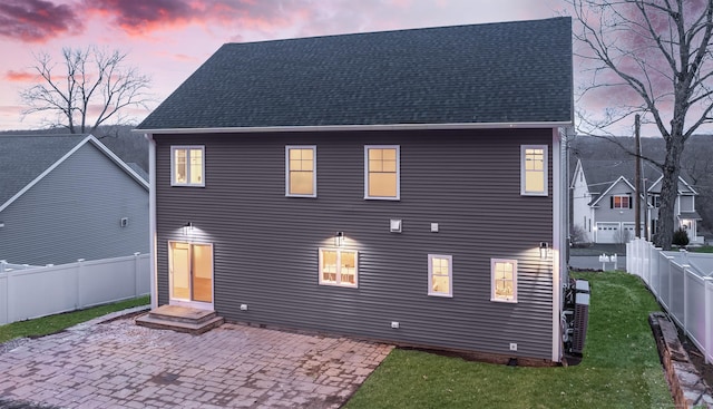 back of property featuring roof with shingles, a patio area, a yard, and a fenced backyard