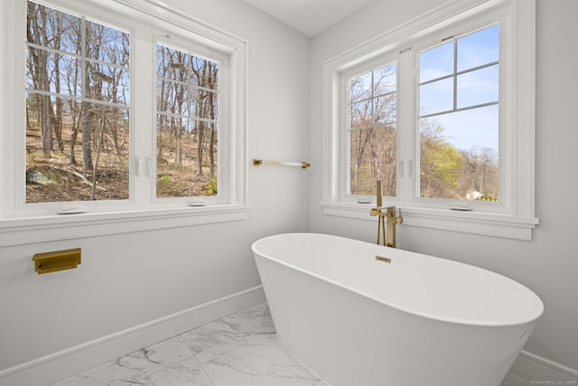 full bathroom featuring a freestanding bath, marble finish floor, and baseboards