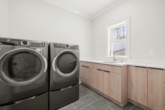washroom featuring dark tile patterned floors, washer and dryer, cabinet space, a sink, and crown molding