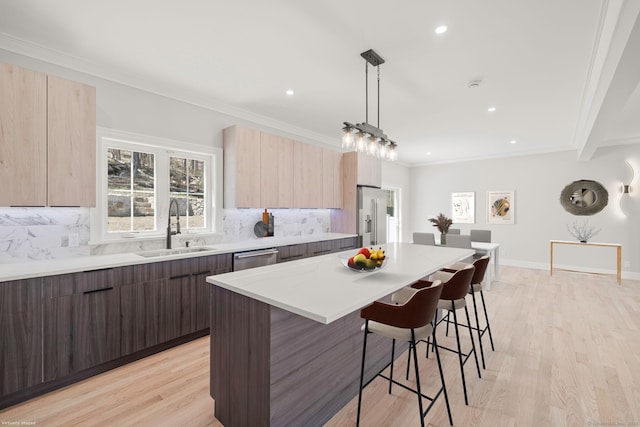 kitchen featuring appliances with stainless steel finishes, light countertops, a kitchen bar, a sink, and modern cabinets