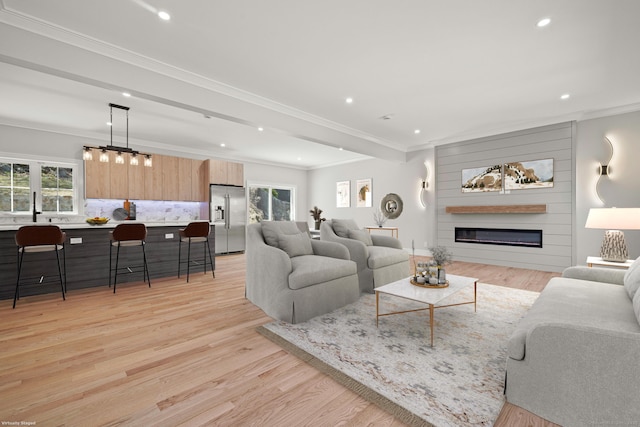 living room featuring a fireplace, recessed lighting, crown molding, and light wood-style floors