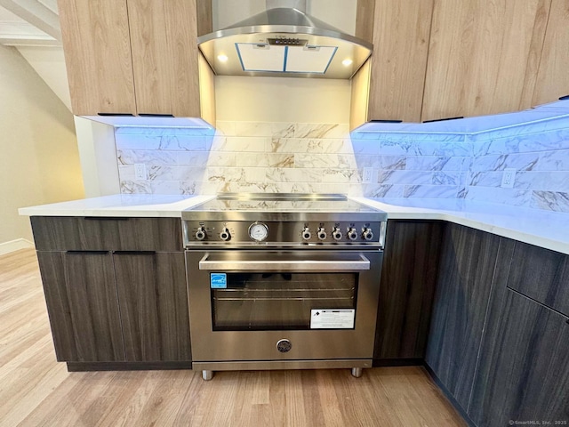 room details with modern cabinets, high end stove, light countertops, light wood finished floors, and extractor fan