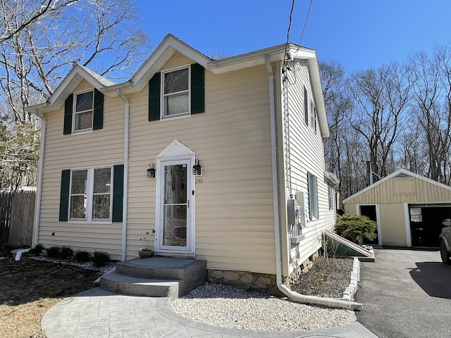 view of front of home with a detached garage, an outbuilding, and fence