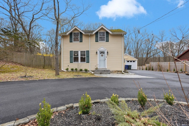 traditional-style house featuring an outbuilding, driveway, fence, and a garage