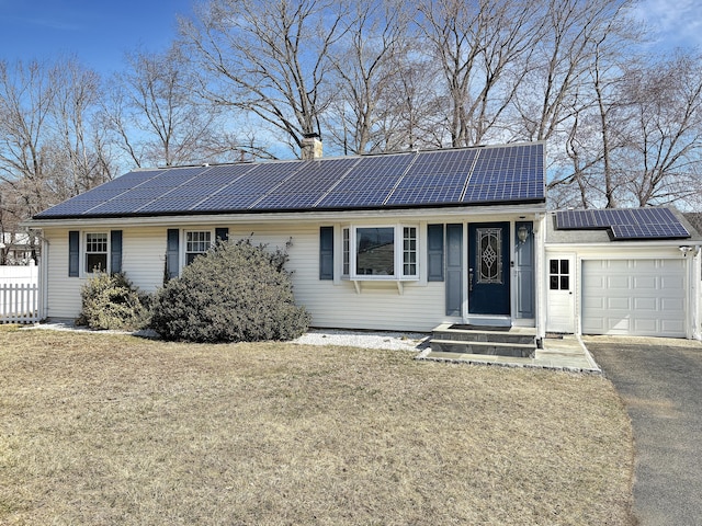 ranch-style home featuring a front lawn, an attached garage, and solar panels