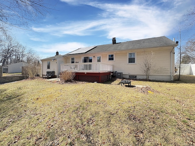 back of house featuring central air condition unit, a yard, a fire pit, a chimney, and a deck