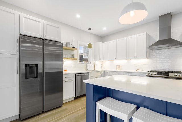 27 Hauser St, Milford, CT 06460 - kitchen with light wood-type flooring, light countertops, wall chimney exhaust hood, a breakfast bar area, and stainless steel appliances