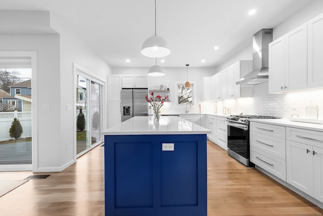 27 Hauser St, Milford, CT 06460 - kitchen with light wood-type flooring, backsplash, a kitchen island, wall chimney exhaust hood, and appliances with stainless steel finishes