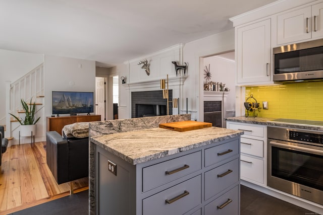 8 Shelter Rock Rd, East Haddam, CT 06423 - kitchen with stainless steel appliances, open floor plan, a fireplace, gray cabinetry, and tasteful backsplash