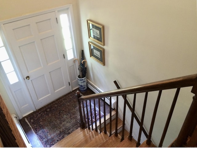 foyer with wood finished floors, plenty of natural light, stairs, and baseboards