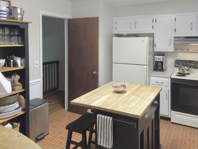 kitchen featuring electric range oven, freestanding refrigerator, brick patterned floors, under cabinet range hood, and white cabinetry