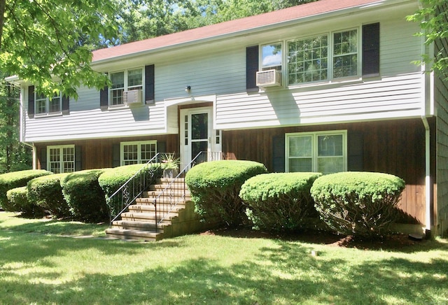 raised ranch with a front lawn and cooling unit