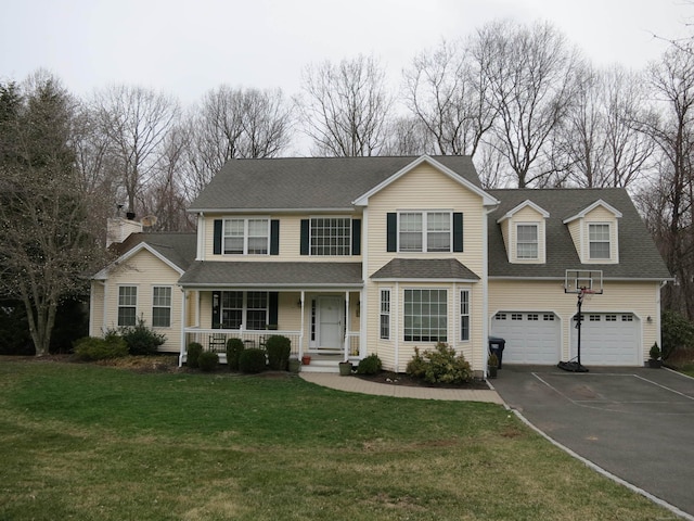 traditional-style home with an attached garage, a front yard, driveway, covered porch, and a shingled roof