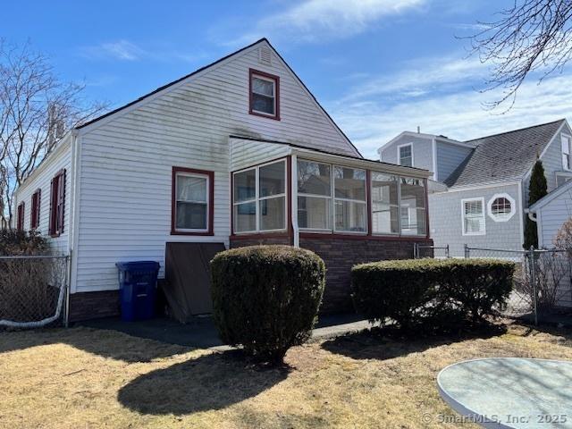 94 Morris St, West Haven, CT 06516 - view of home's exterior featuring fence, a lawn, and a sunroom